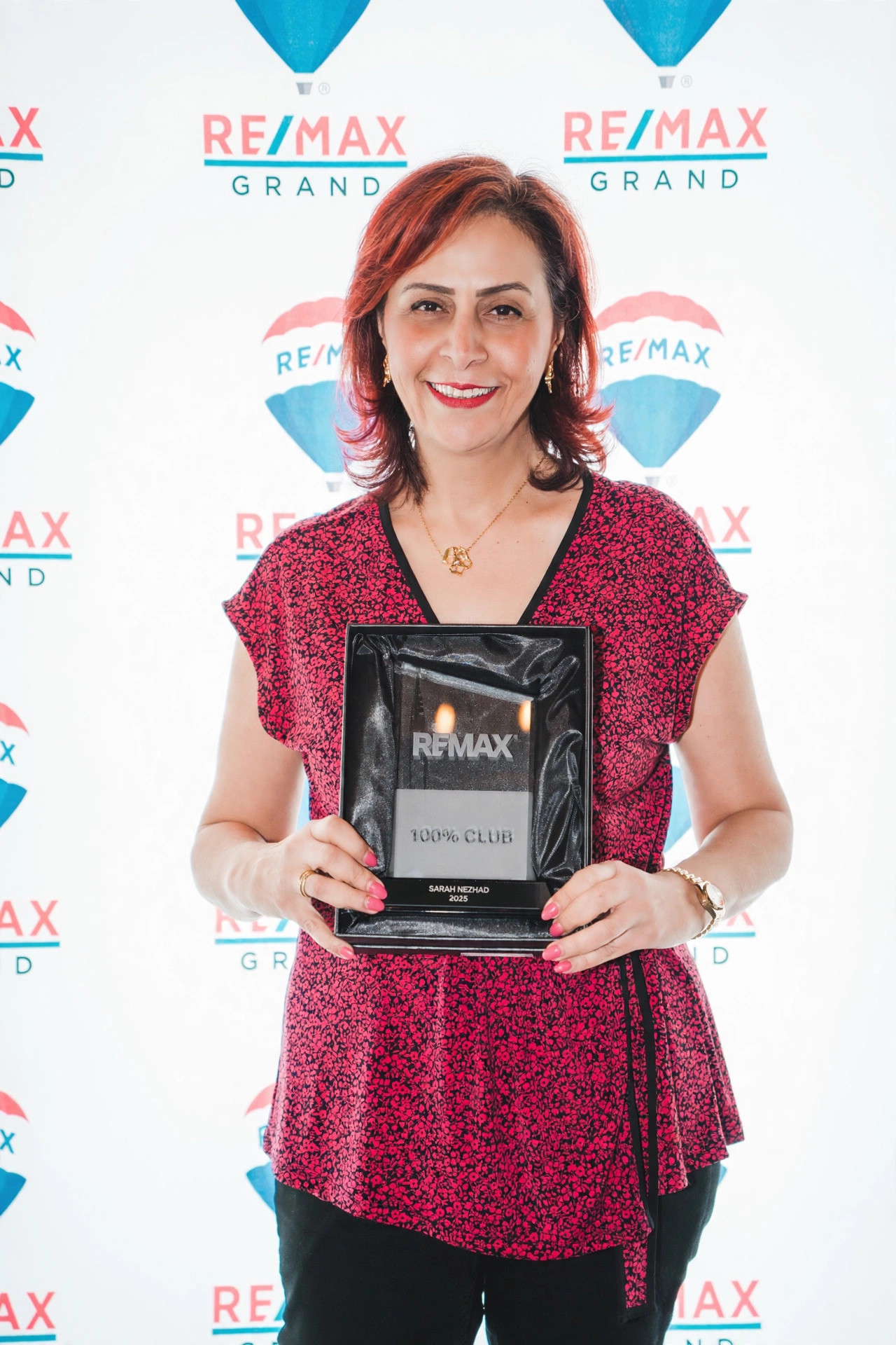 Sarah Nezhad holding her RE/MAX 100% Club award